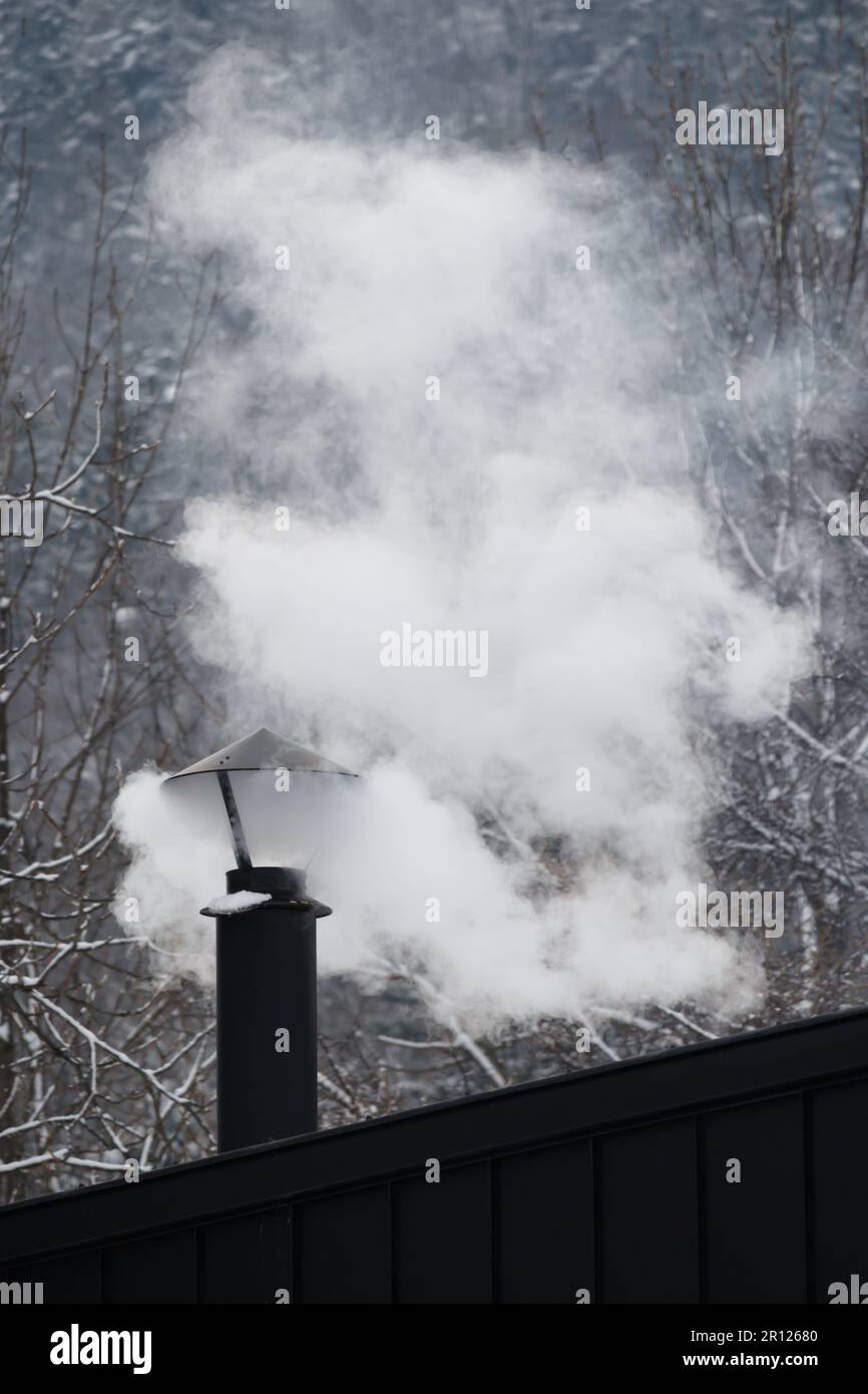 Weißer Rauch steigt im Winter aus dem Kamin Stockfoto