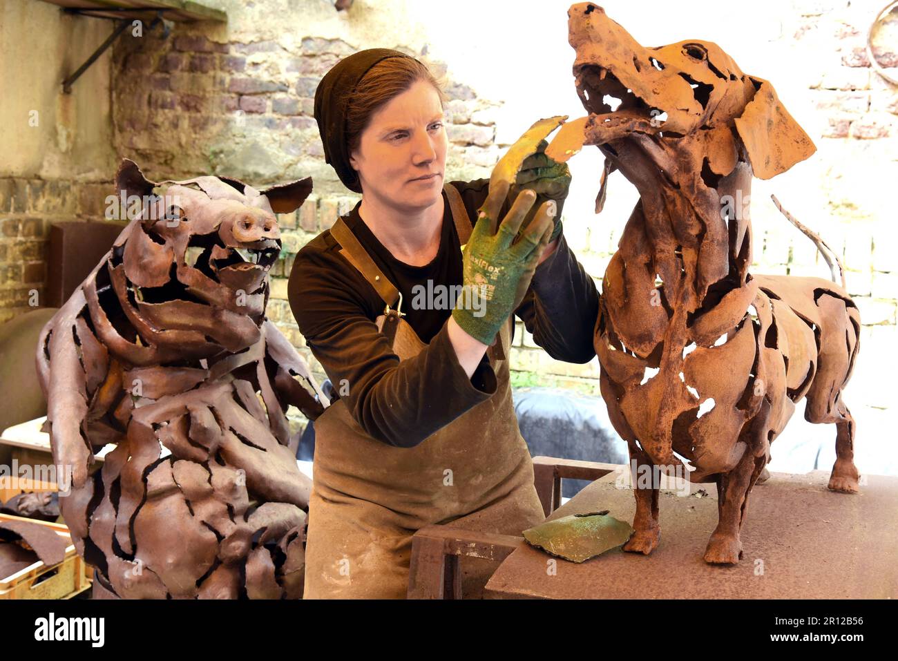PRODUKTION - 05. Mai 2023, Sachsen, Leipzig: Stahlkünstlerin Dana Meyer, die in ihrem Hinterhof auf einem 1,10 Meter langen Dachshund einer neuen Anlage, einem Metallteil, lag. Die ungewöhnliche lebensgroße Stahlskulptur, zusammen mit kleineren Metallinsekten in Glas, ist eines der Werke, die der Künstler freihändig und ohne Plastikdesign schmiedet. Sie verwendet meist gefundene Stahlplatten, um geschmiedete Teile herzustellen, die sie zu ungewöhnlichen Figuren wie einem Puzzle mit einem Schneidbrenner und Schweißgeräten zusammenbaut. Sie wird mit ihren Werken von 12,5.-20.08.23 in der Galerie Rothamel in Fran vertreten Stockfoto