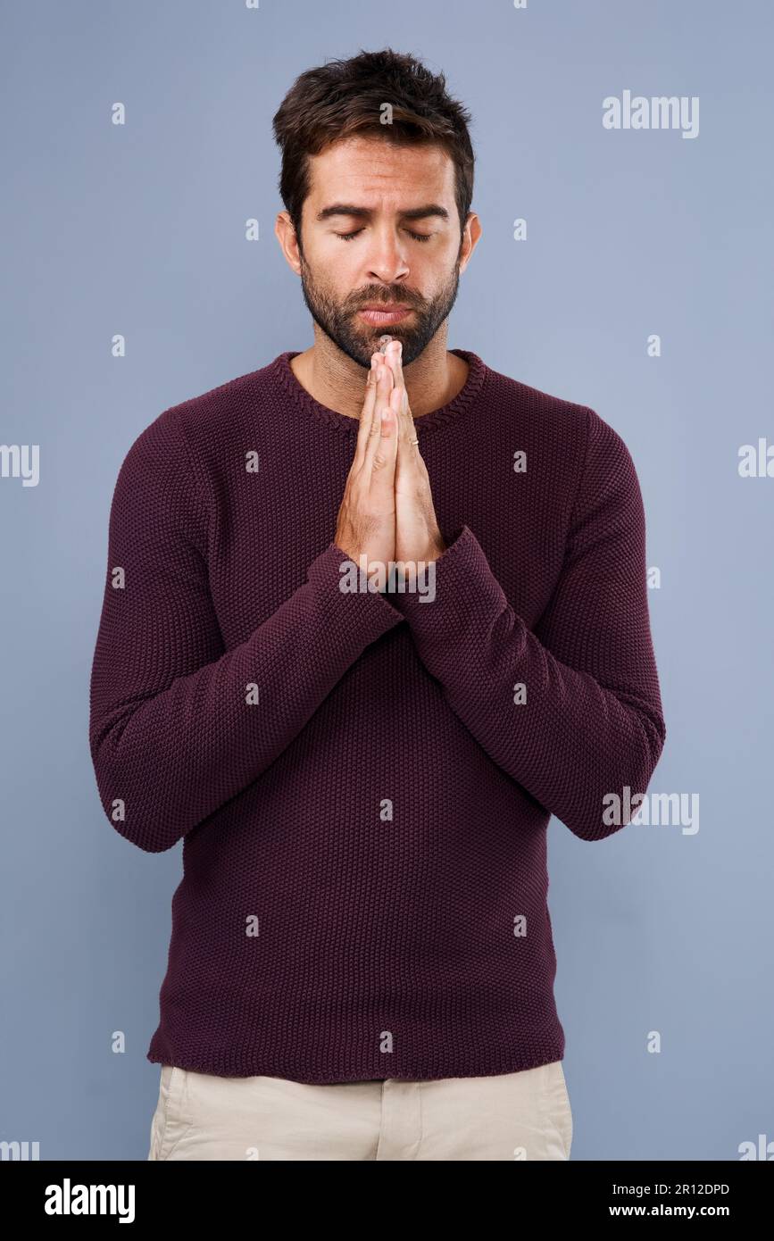 Lieber Gott... Studio-Aufnahme eines gutaussehenden jungen Mannes, der vor grauem Hintergrund betet. Stockfoto