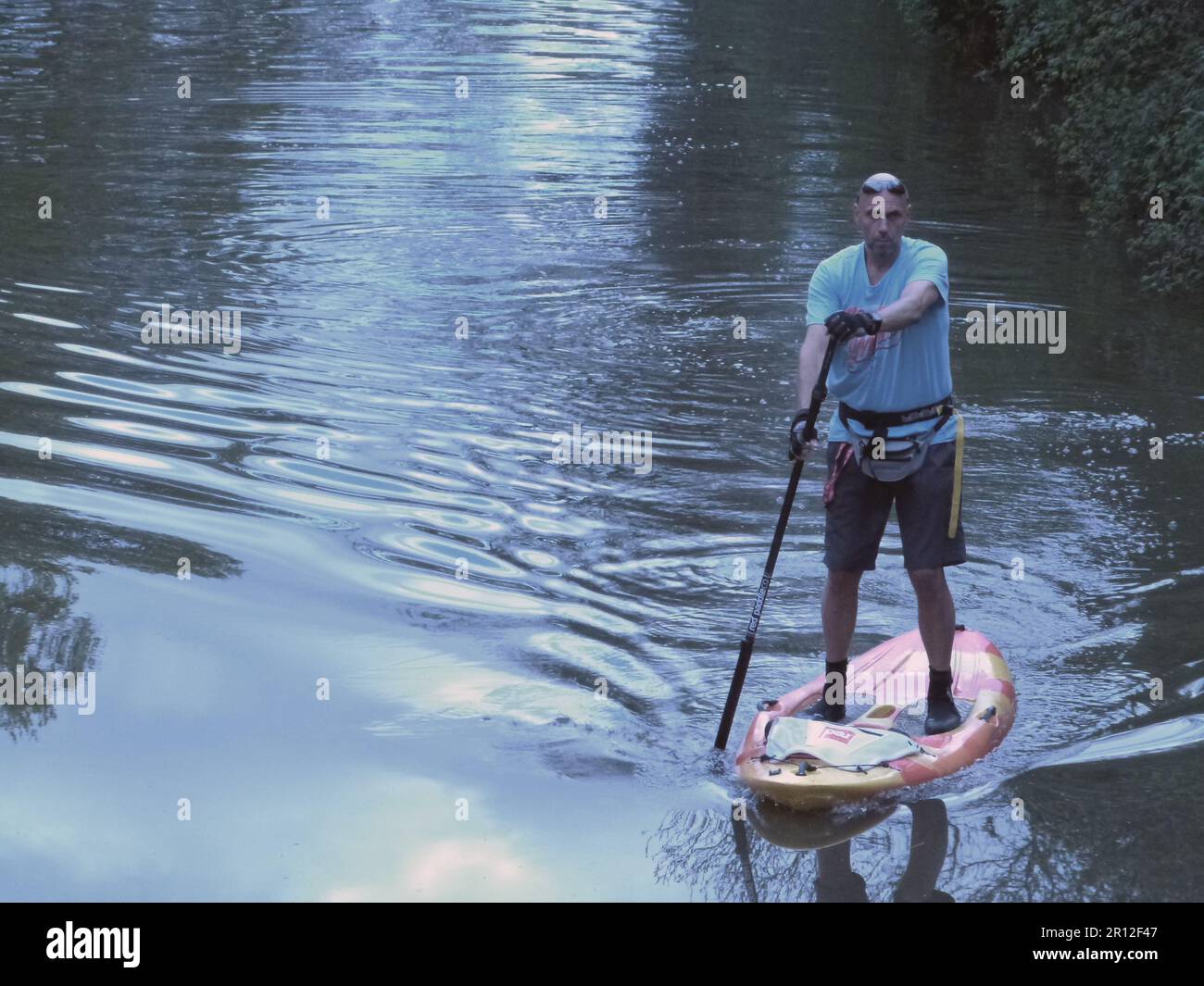 Auf einem Paddelbrett auf einem Kanal nahe Wootton Wawen bei Stratford-upon-Avon Warwickshire balanciert dieser einsame, reife Mann Stockfoto