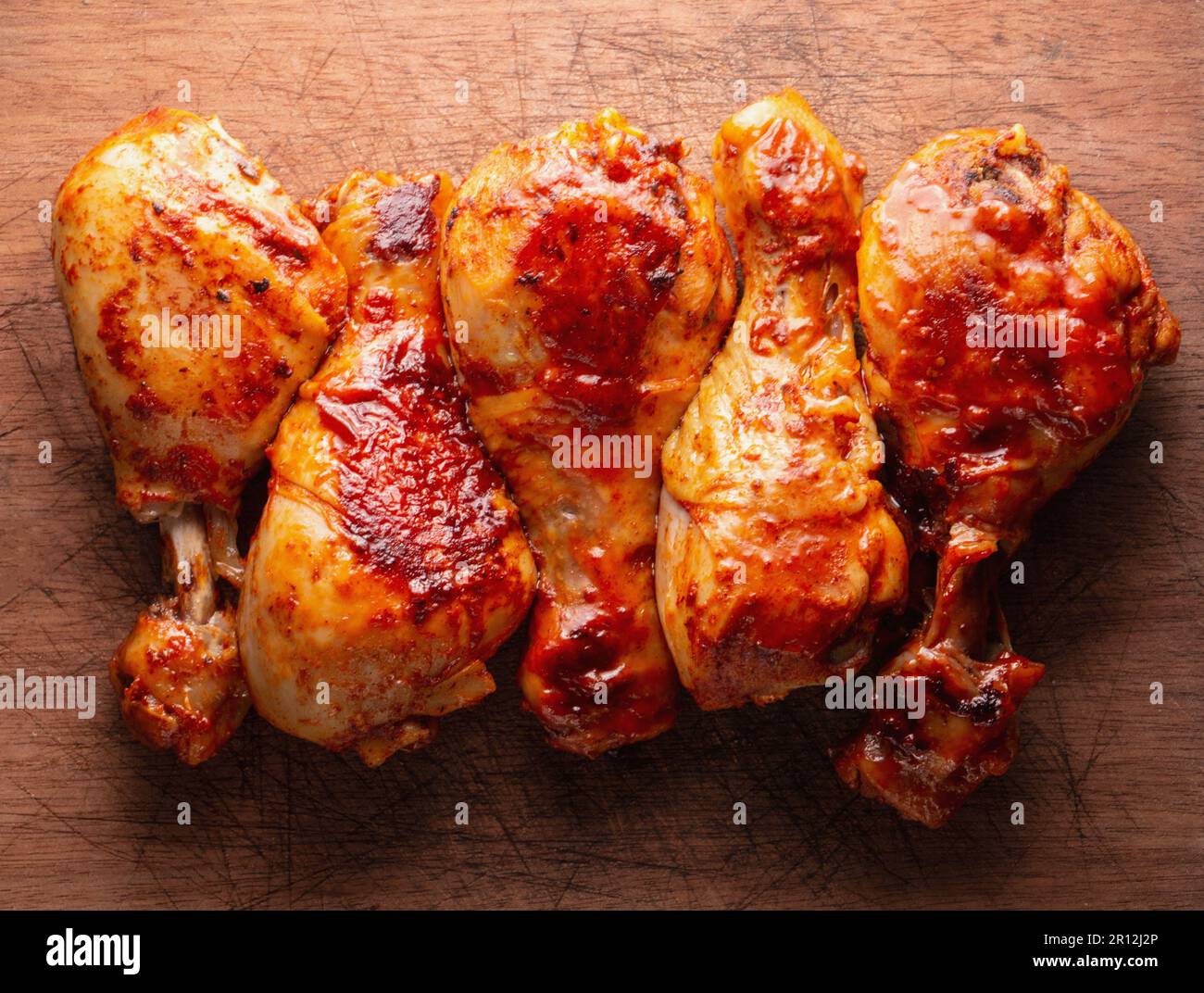 Gebratene Hähnchenschenkel auf einem Holzbrett, Draufsicht. Stockfoto