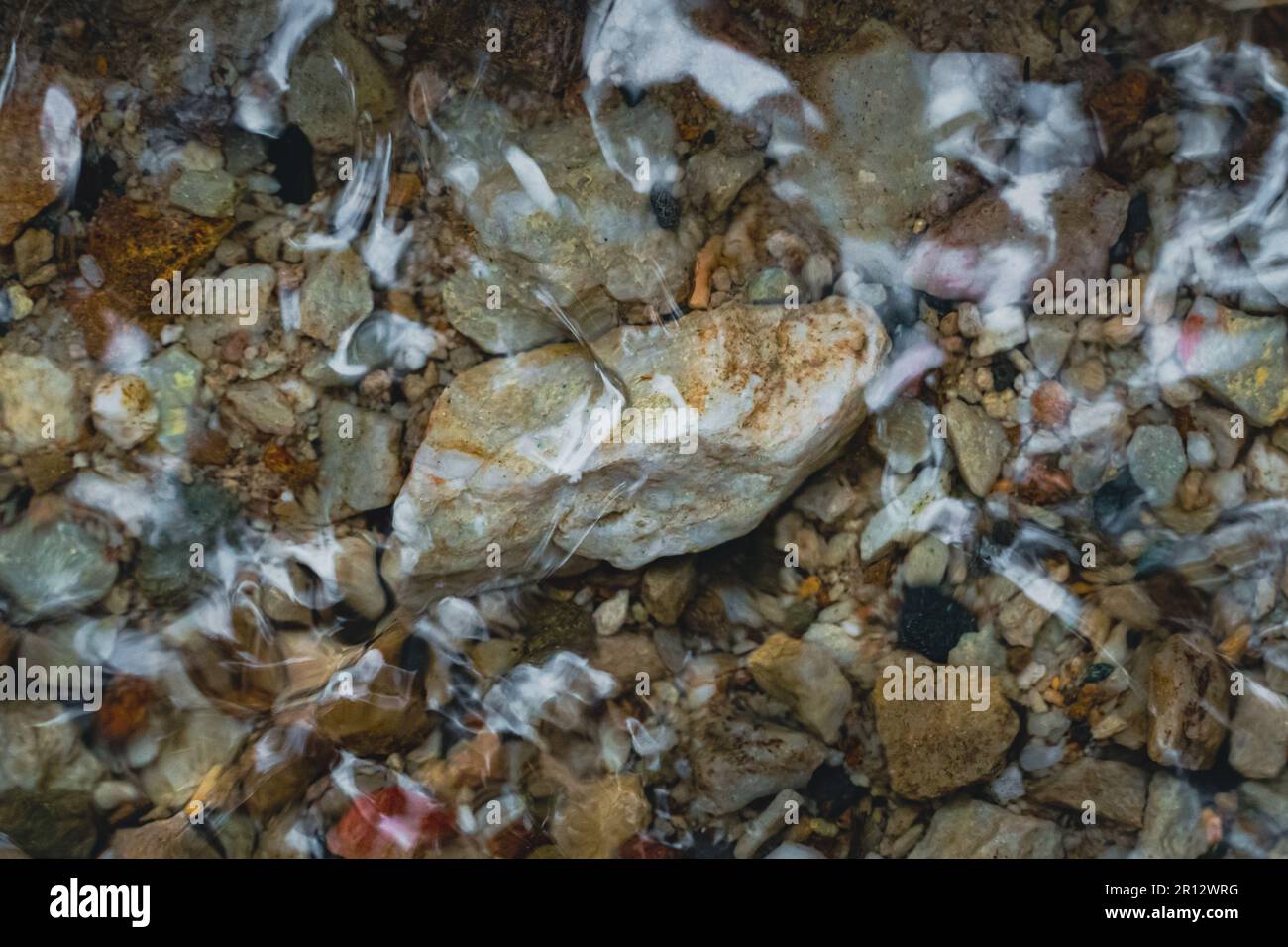 Eine Reihe von großen und kleinen Steinen unter dem klaren Wasser im Bach. Stockfoto