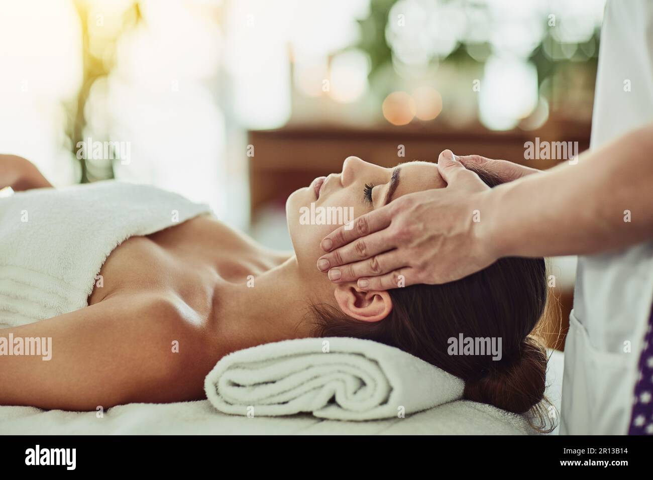 Verbringen Sie etwas Zeit mit sich selbst. Eine attraktive junge Frau, die in einem Schönheitssalon massiert wird. Stockfoto