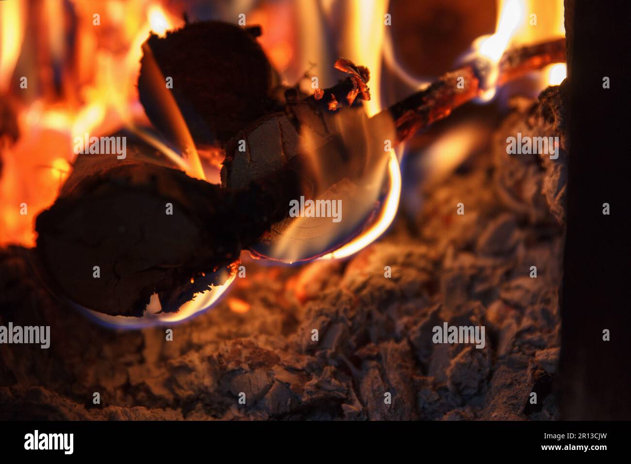 Ein helles Feuer mit hoher Temperatur aus natürlichem Brennholz und Ästen brennt im Ofen und heizt das Haus in der kalten Jahreszeit, mit Schönheitshorizont Stockfoto