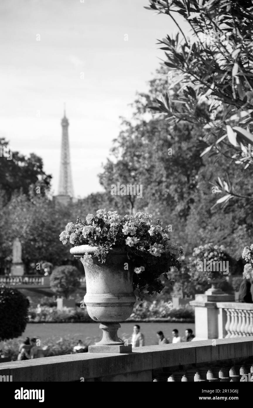 Paris, Frankreich. Blick vom Jardin du Luxembourg auf den Eiffelturm. Selektiver Fokus auf Blumenvase. Verschwommene, entspannende Touristenmassen im Park. Schwarzweißfoto Stockfoto