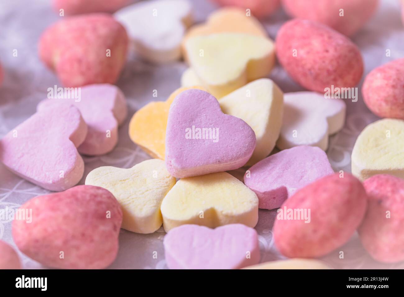 Eine Auswahl an Zucker- und rosafarbenen Schokoladenherzen, Blick von oben, Pastellfarben Stockfoto