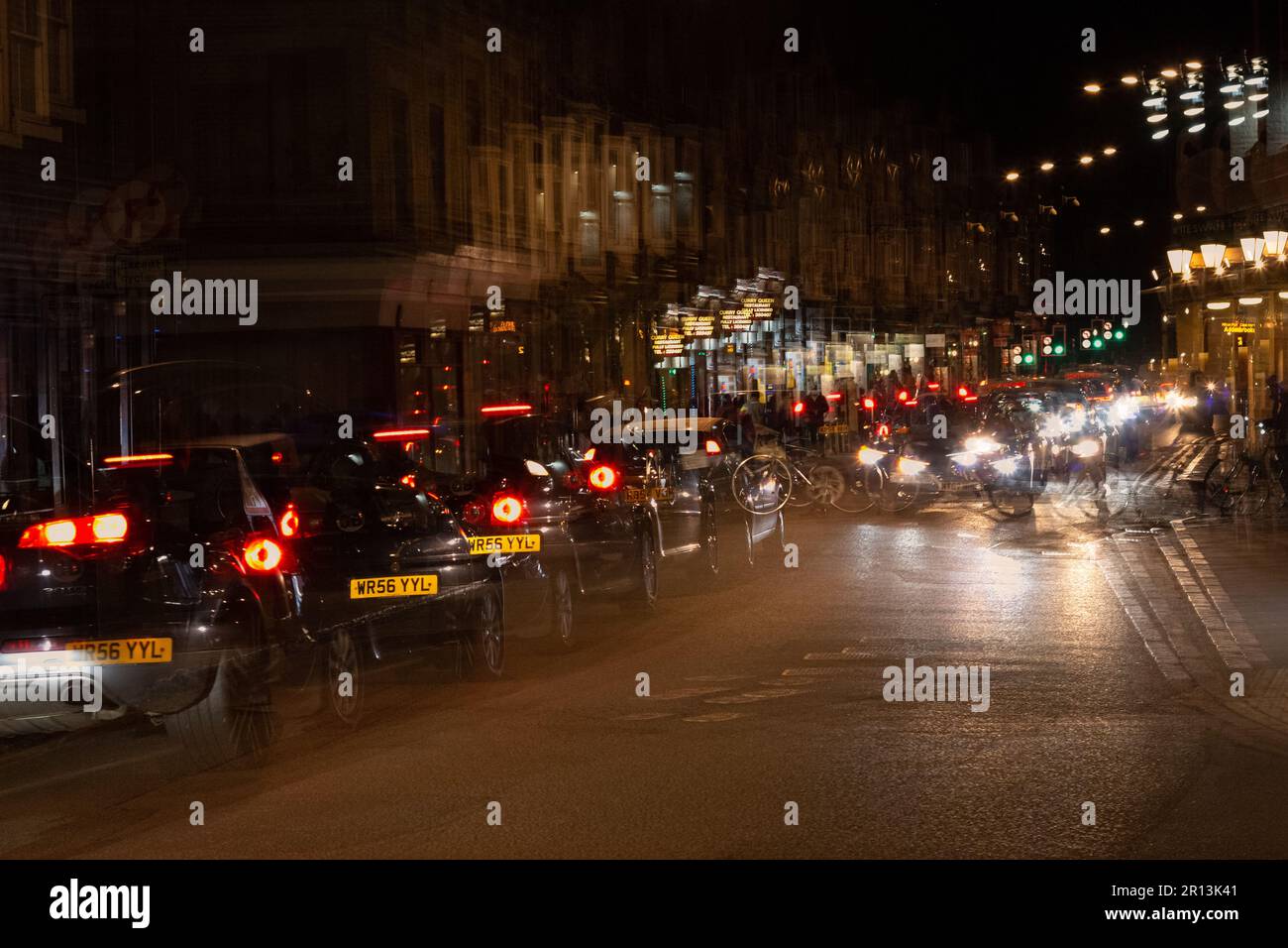 Mehrere Belichtungsfotos von Mill Road, geschäftig mit Verkehr und Fahrrädern bei Nacht, Cambridge, Großbritannien Stockfoto