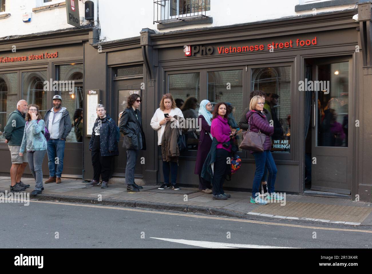 Vor dem Pho Vietnamese Street Food Restaurant auf der Wheeler Street, Cambridge, Großbritannien, warten viele Leute Stockfoto