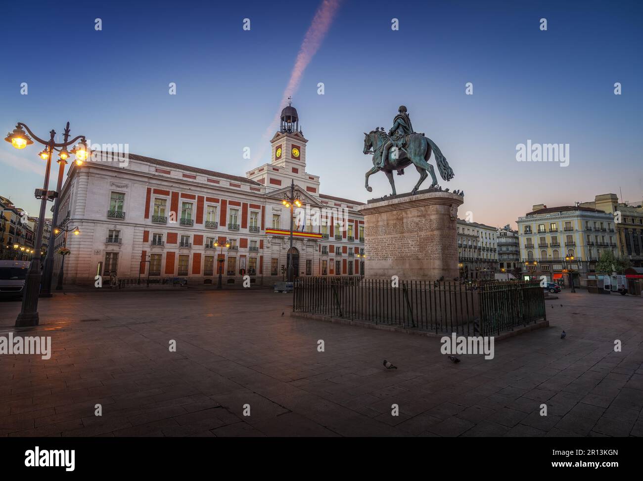 Puerta del Sol bei Sonnenaufgang mit Denkmal für König Karl III. (Carlos III) und königlichem Haus des Postamts - Madrid, Spanien Stockfoto