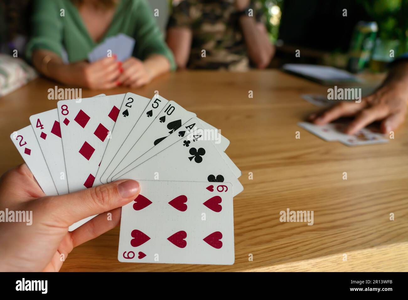 Eine Frau, die mit Freunden Karten spielt. Stockfoto