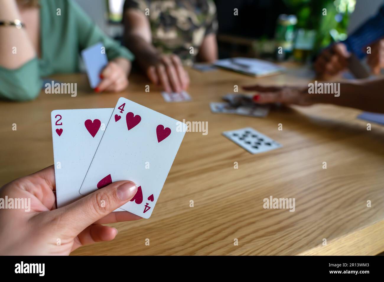 Eine Frau, die mit Freunden Karten spielt. Stockfoto