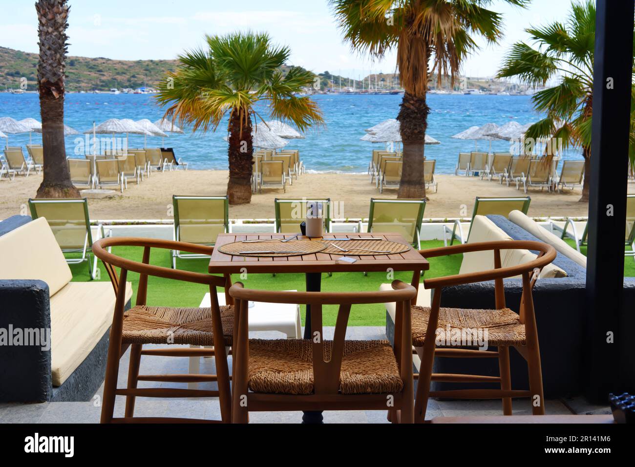 Tische im Restaurant mit blauem Meer und Palmen im Hintergrund Stockfoto