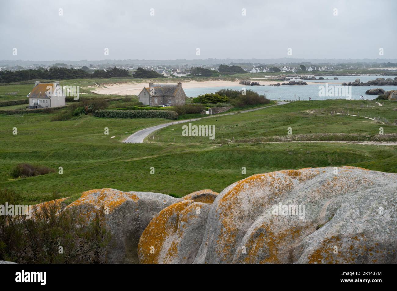 Hütten an der bretonischen Küste mit großen Felsbrocken im Vordergrund. Stockfoto