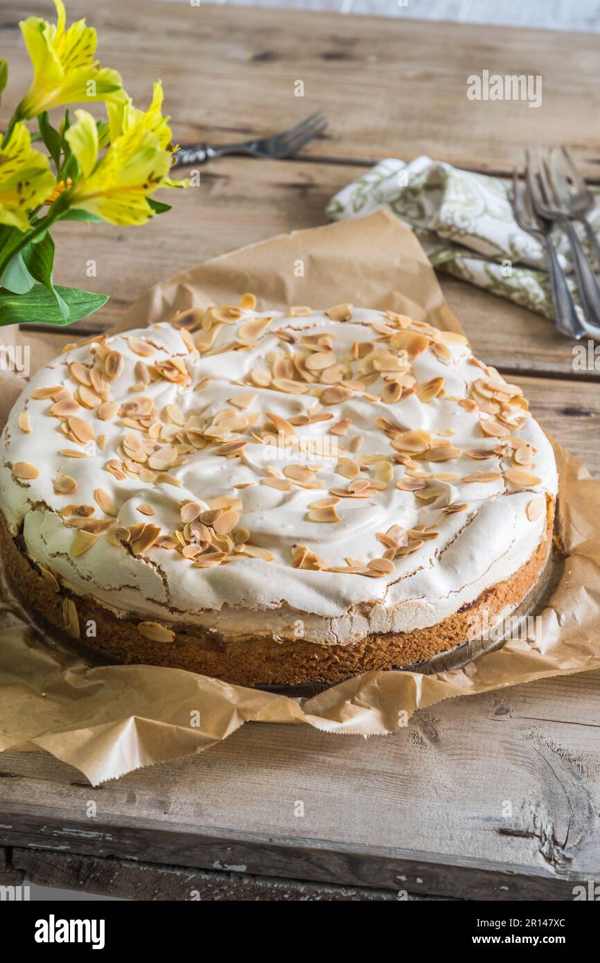 Rhabarberkuchen mit Baiser-Belag und gerösteten Mandeln auf einem alten rustikalen Holztisch, vertikal Stockfoto