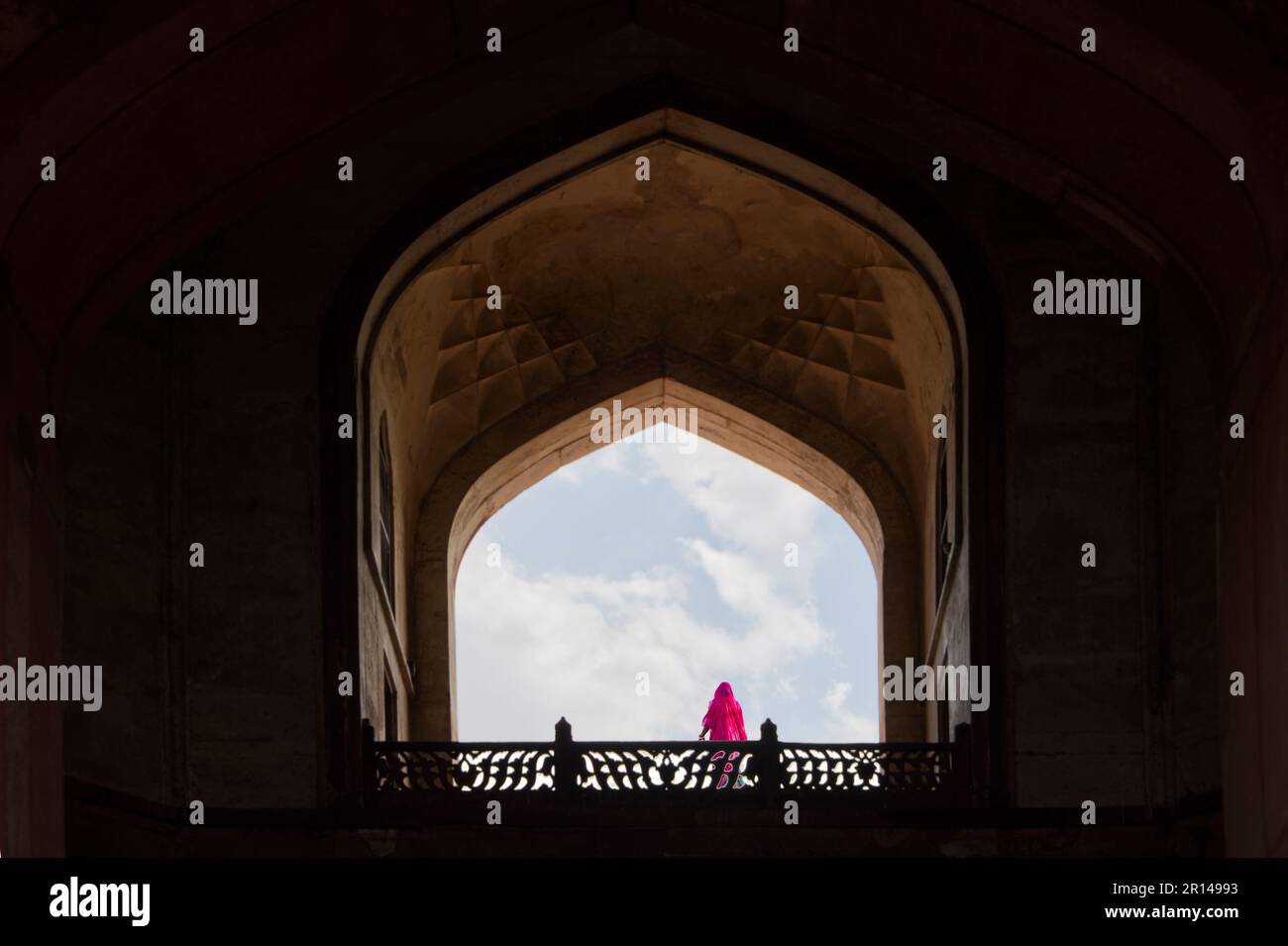 Indianerin in rosa Sari auf dem Balkon eines Monuments vor dem wolkigen blauen Himmel Stockfoto