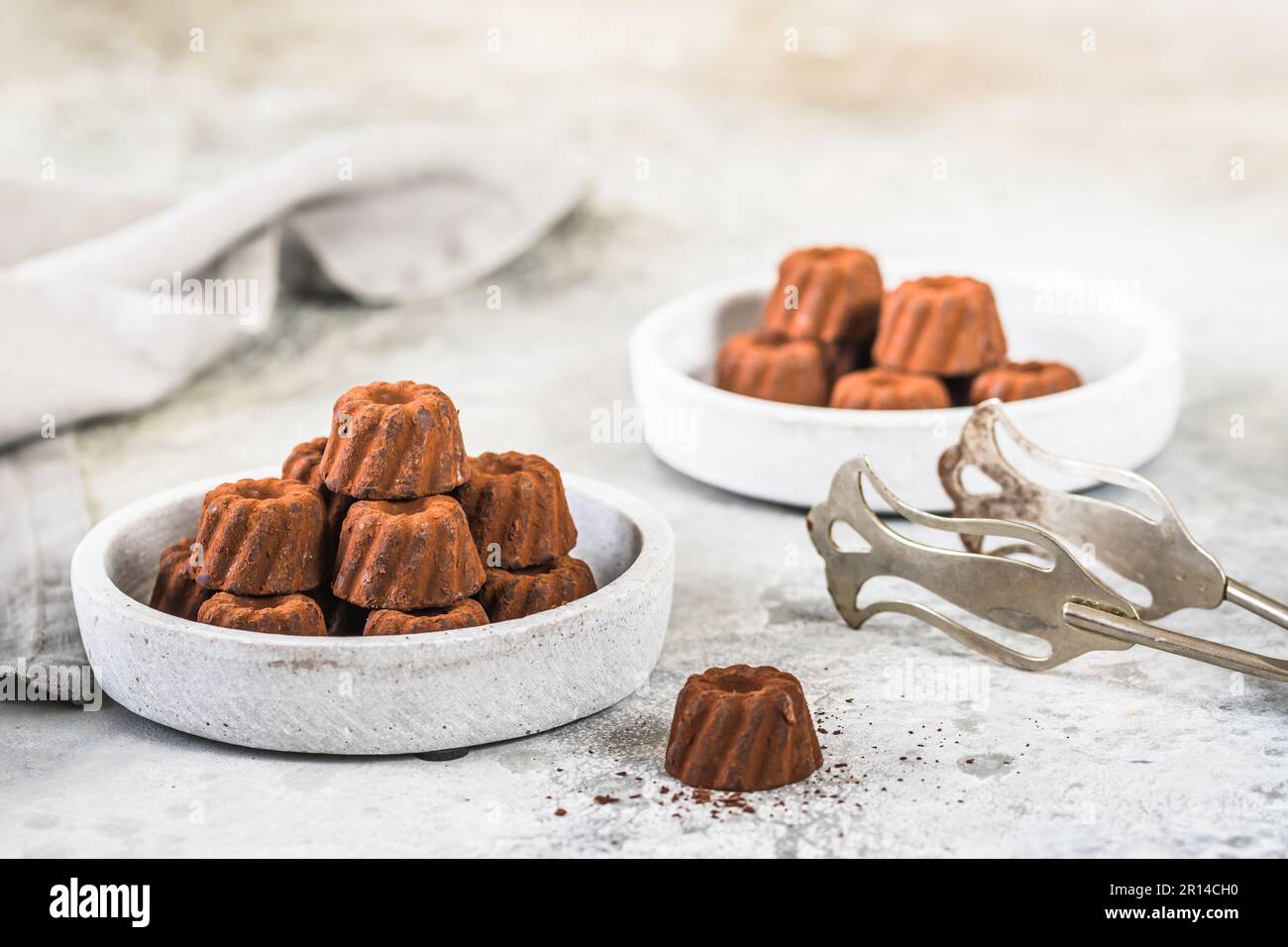 Schokoladenpralinen in Form von kleinen Guglhupf-Törtchen, mit Kakao bestaubt, auf hellgrauem Hintergrund Stockfoto
