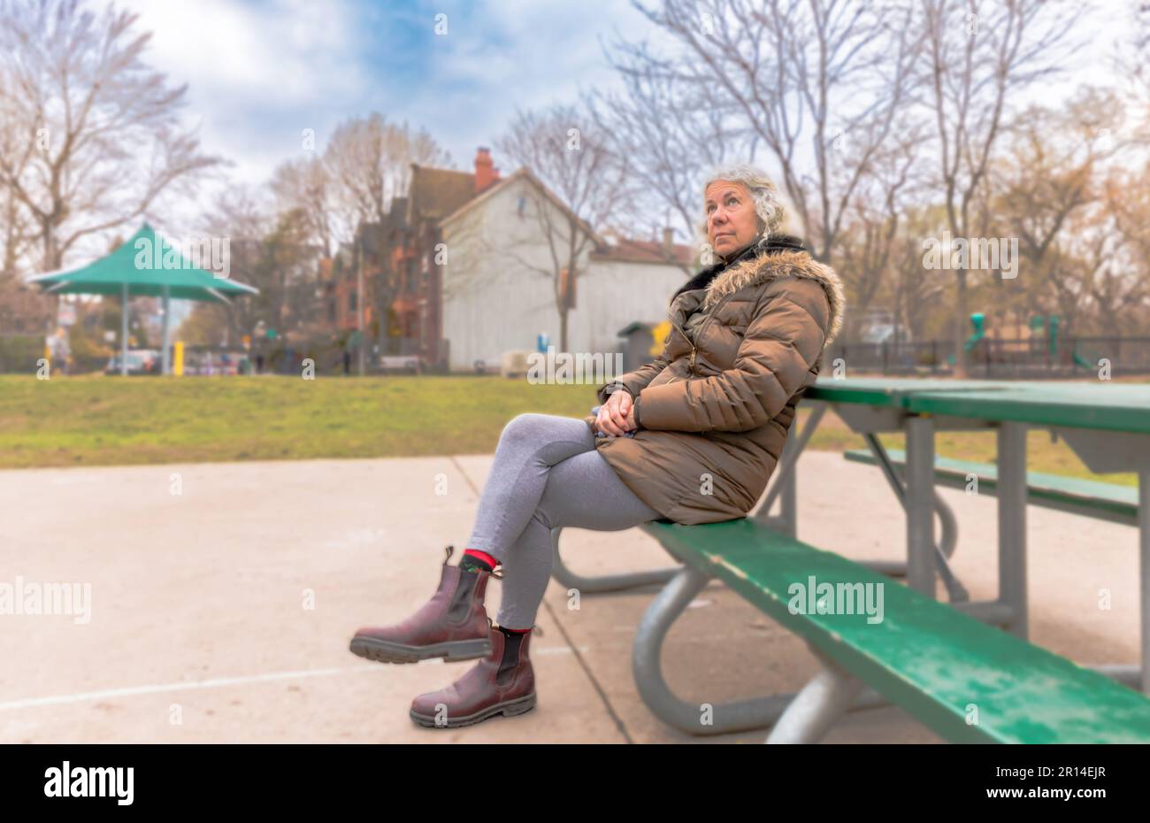 Eine ältere Frau sitzt allein auf einer Parkbank Stockfoto