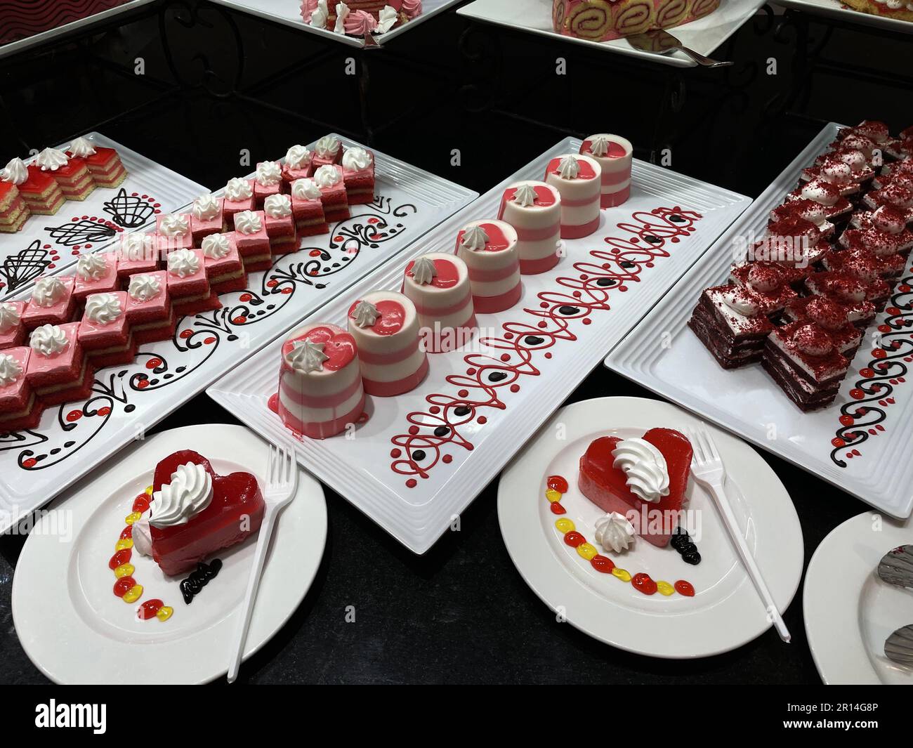 Showcase mit Süßigkeiten. Farbig сakes auf weißen Platten auf schwarzem Tisch. Stockfoto