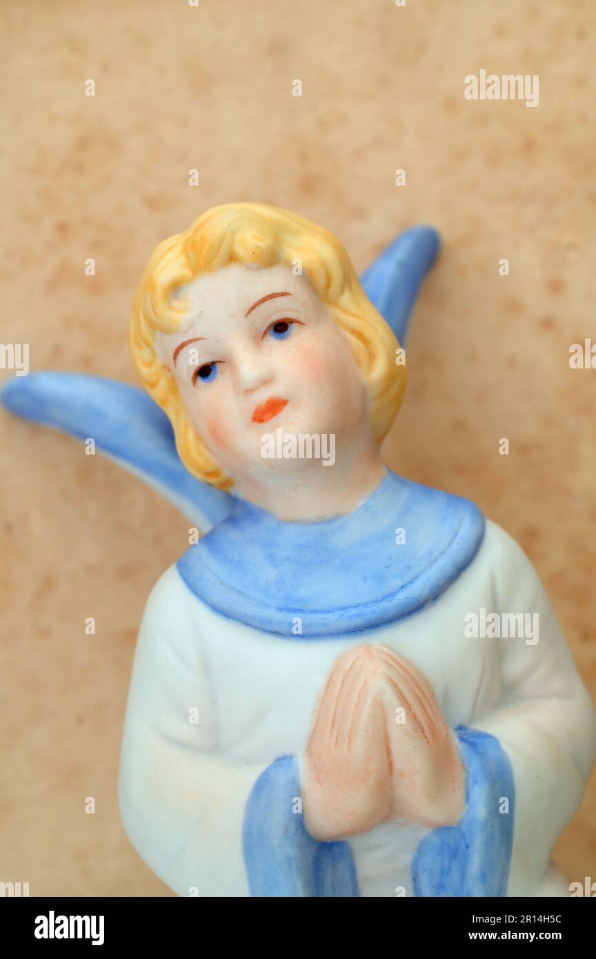 Porzellanmodell einer jungen Frau mit Engelsflügeln, die in den Himmel blickt, mit gefesselten Händen im Gebet Stockfoto