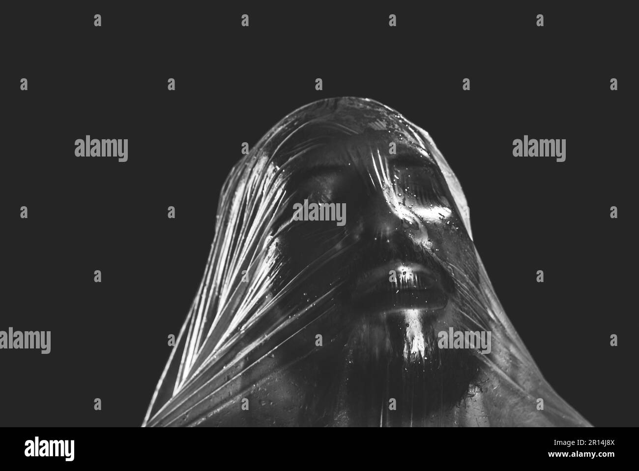 Mann mit Plastiktüte über dem Kopf, erstickt. Schwarzweiß-Aufnahme. Schmerzausdruck. Stockfoto