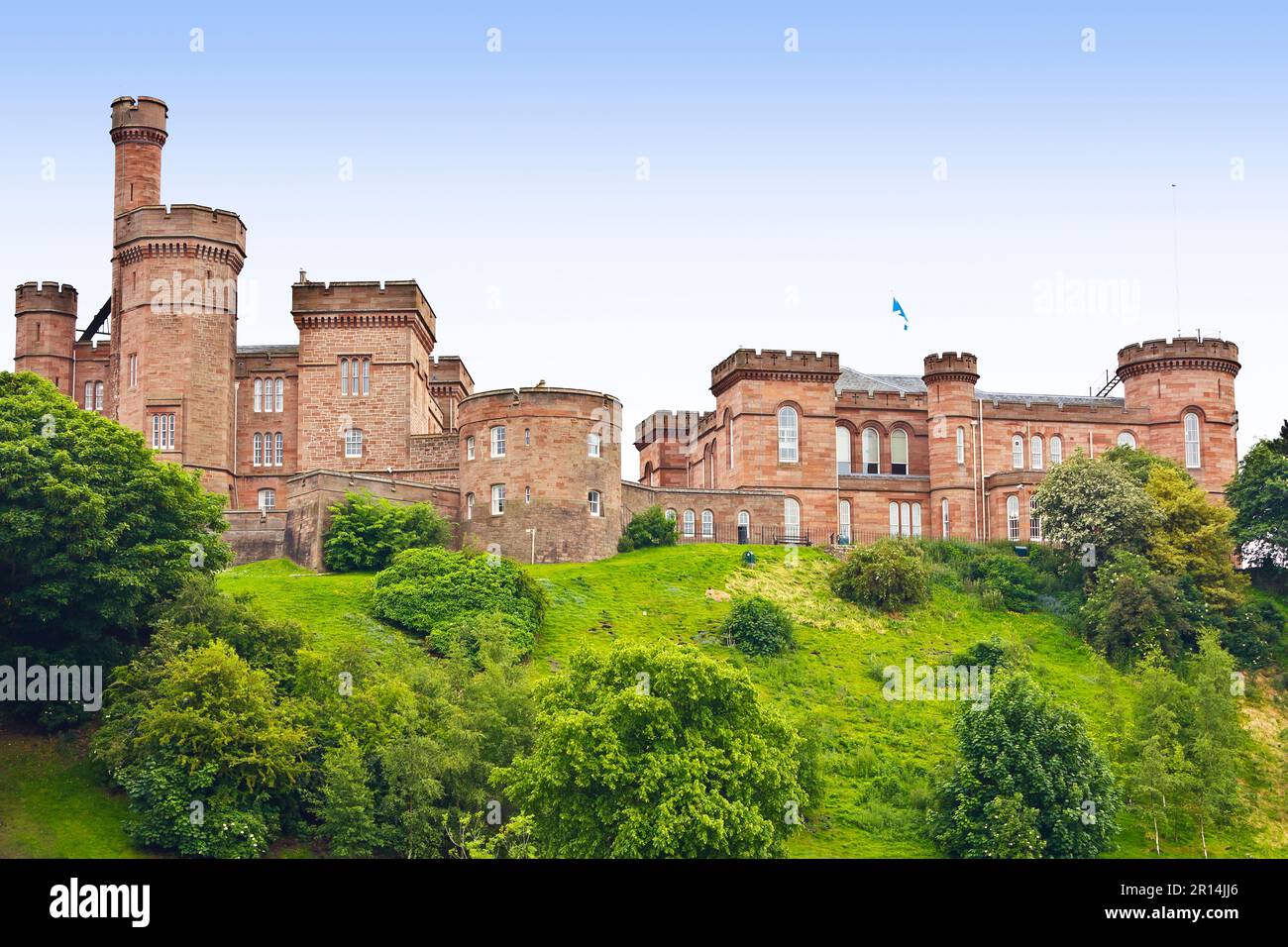 Altes Inverness Castle, erbaut aus rotem Sandstein auf einem grünen Hügel im Sommer, vom Fluss Ness aus gesehen. Schottland, Großbritannien, Europa. Stockfoto