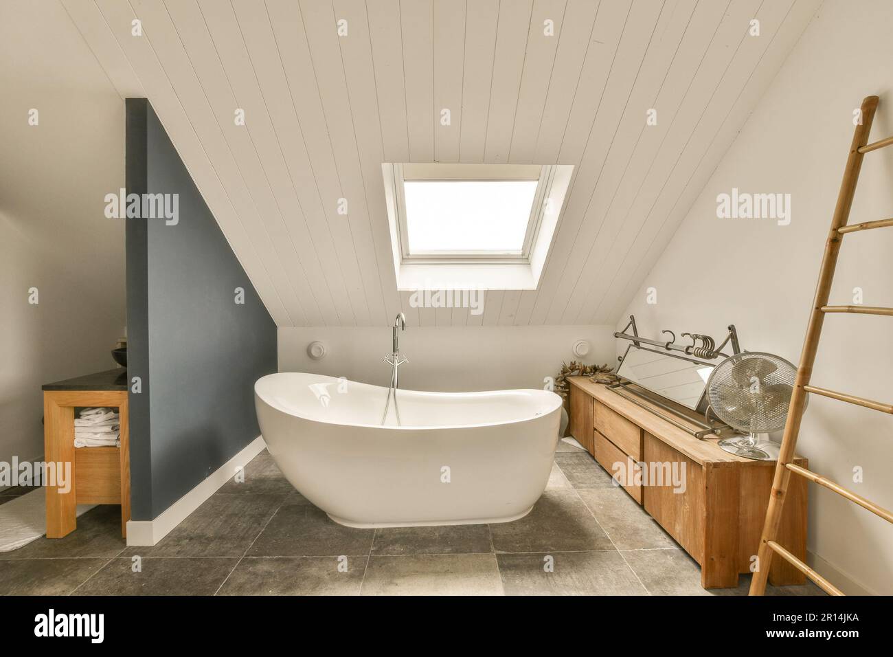 Ein Badezimmer mit einem Oberlicht über der Badewanne und Holzleitern an  der Wand neben der Badewanne Stockfotografie - Alamy