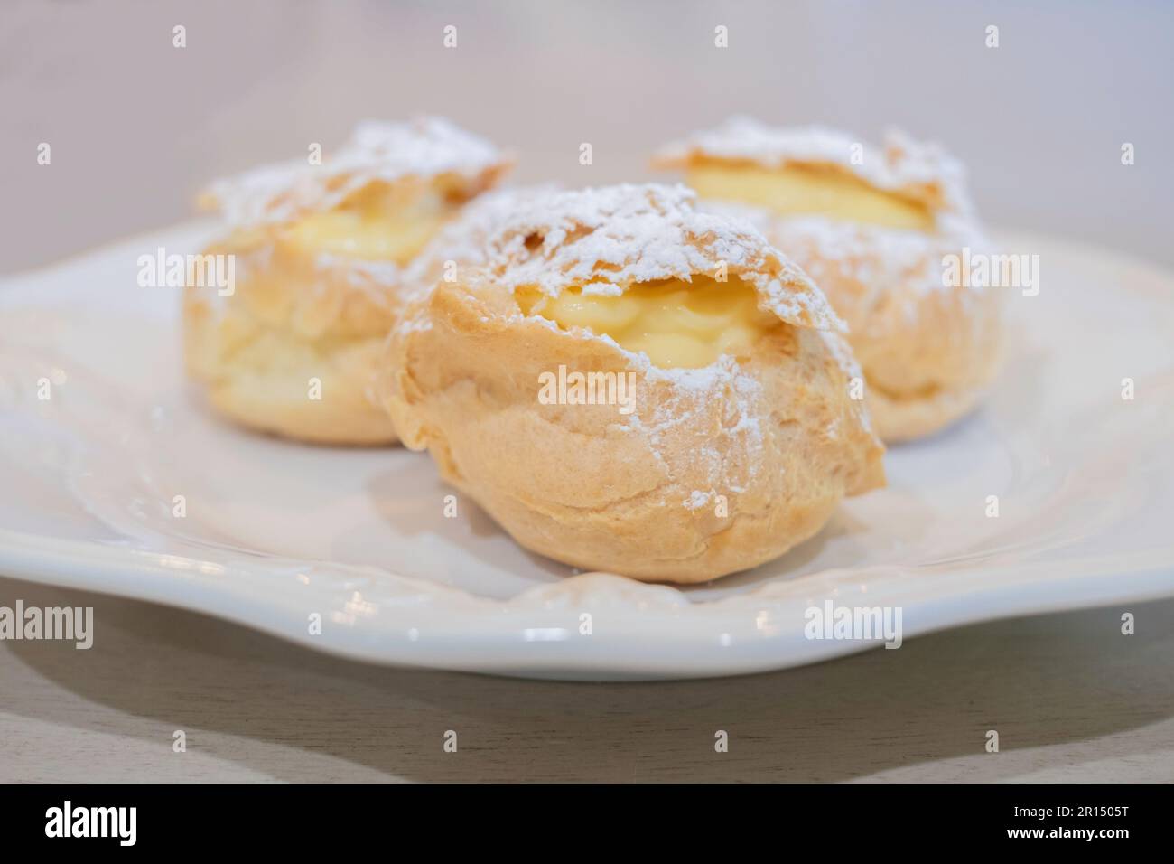 Drei Sahnepuffs, Pate a Choux, gefüllt mit Vanillecreme Pudding und gestreut mit Puderzucker. Süßes Dessert. USA. Stockfoto