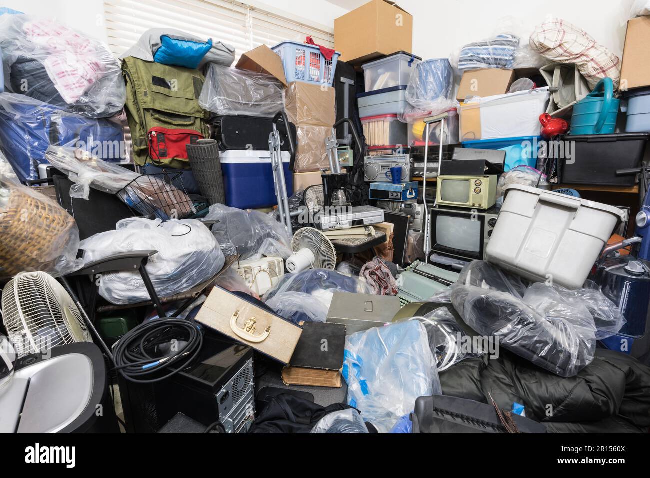 Hoarder House Schlafzimmer vollgepackt mit Kleidertaschen, Haushaltsgegenständen, alter Elektronik und anderem Müll. Stockfoto