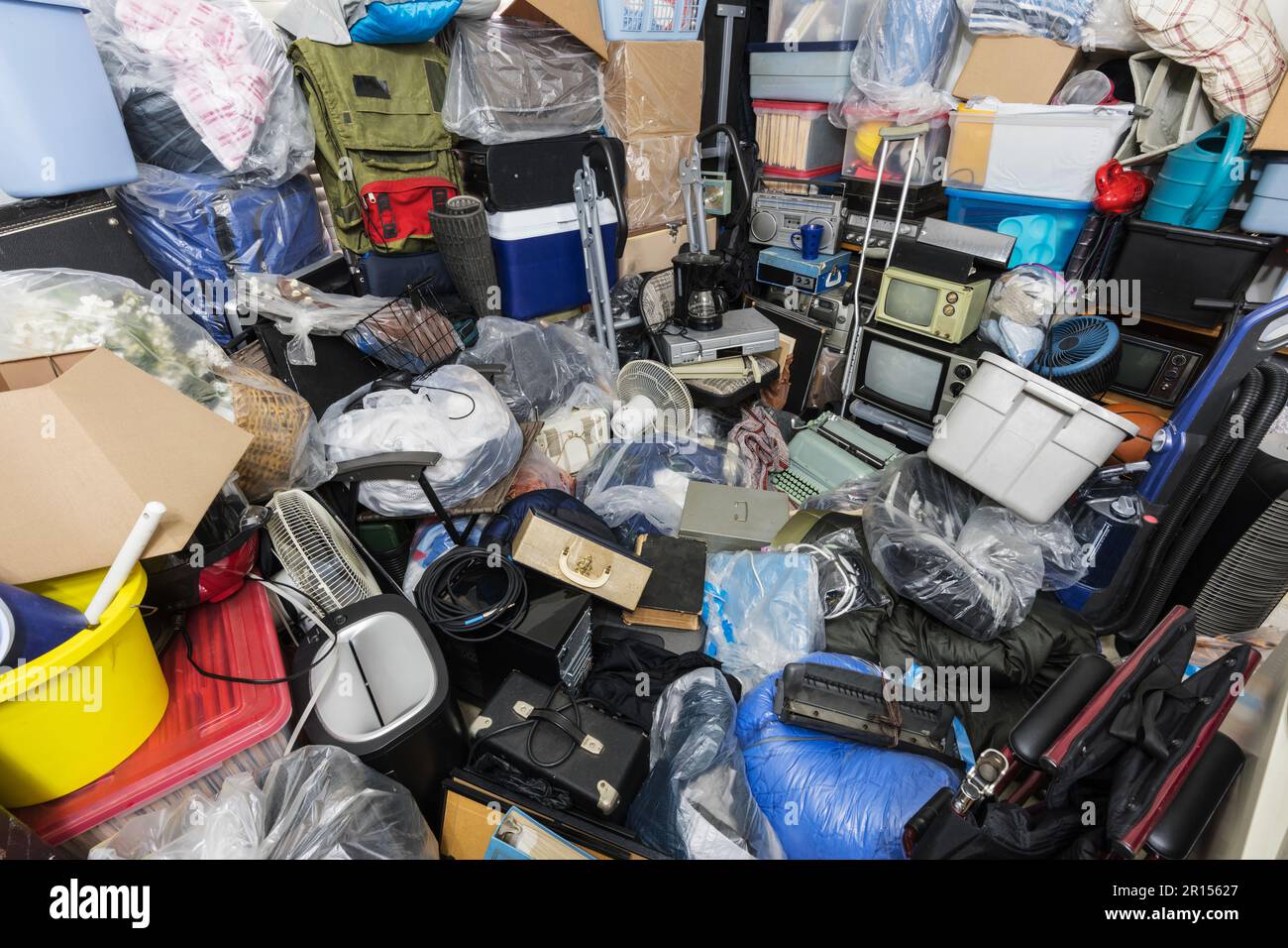 Hoarderhaus mit Kleidertaschen, Haushaltsgegenständen, alter Elektronik und anderem Müll. Stockfoto
