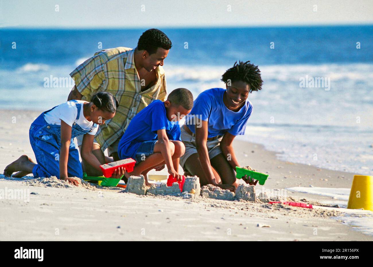 Das afroamerikanische Familiengebäude besteht aus Sandskulpturen am Strand Stockfoto
