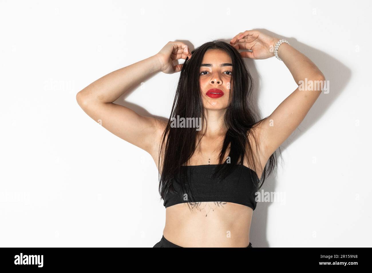 Hübsche braune, gehäutete Latina Teenagerin, die sich mit beiden Händen am Kopf vorne posiert Stockfoto