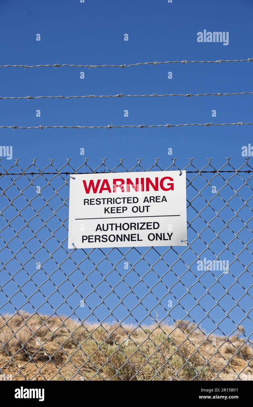 Warnung Sperrgebiet Halten Sie autorisiertes Personal fern Schild nur auf einem Stacheldraht Kettenzaun mit blauem Himmel in der Wüste Stockfoto