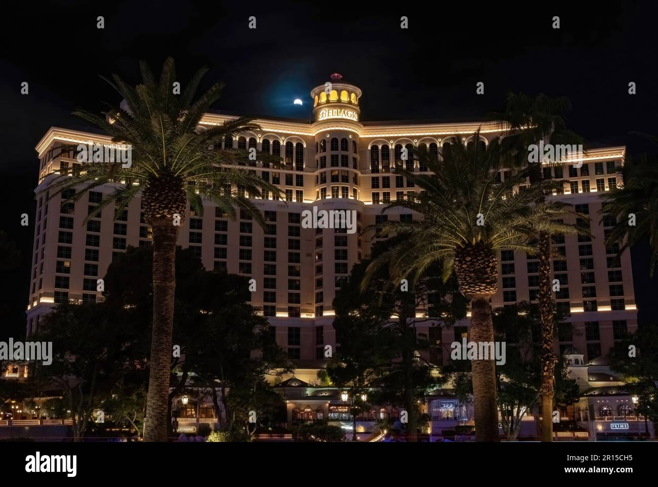 Das Bellagio Hotel and Casino in Las Vegas, Nevada, USA, mit Palmen vor der Tür während einer Mondfinsternis direkt vor dem Turm des Resorts. Stockfoto