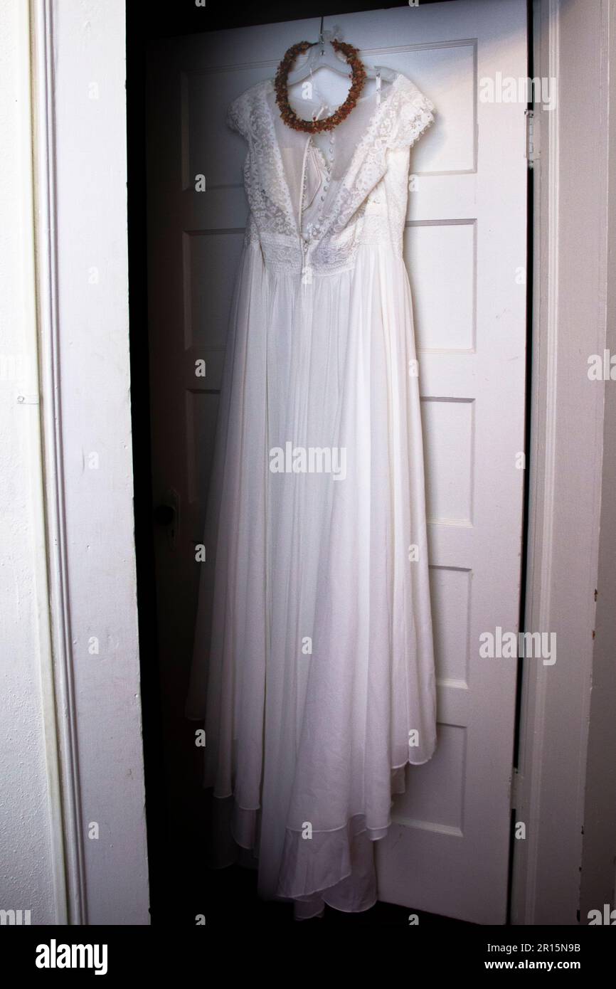 boho Weißes Hochzeitskleid Korsett aus der Nähe mit orangefarbenem Kopfkranz, Blumenkrone, geblümtem Kopfstück, das in der Tür liegt Stockfoto