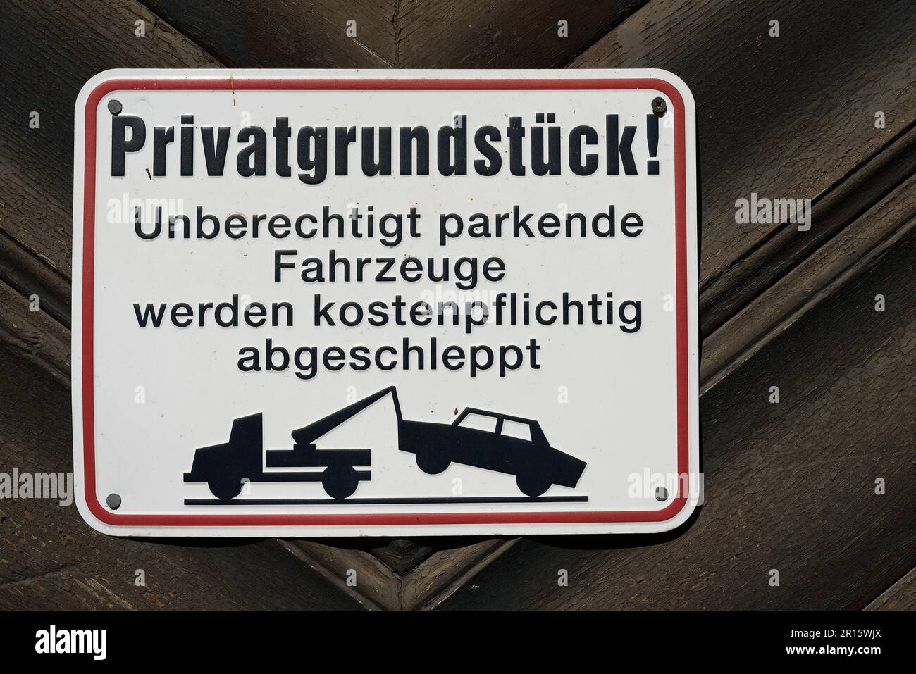 Schild mit deutscher Inschrift Privatgrundstück, parkende Autos werden abgeschleppt. Übersetzung: Privateigentum, geparkte Autos werden abgeschleppt Stockfoto