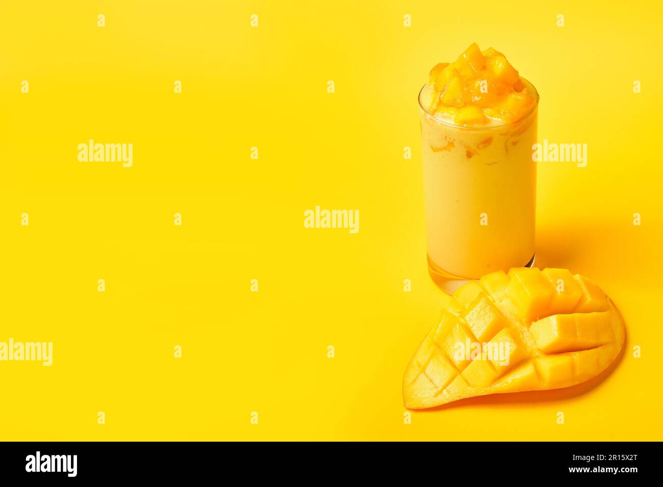 Saftiger Mango Smoothie mit frischen Mangoscheiben auf gelbem Hintergrund.Thai Sweet Mango Smoothie.Summer Drinks.Yellow Drinks.frischer Fruchtsaft für die Gesundheit. Stockfoto