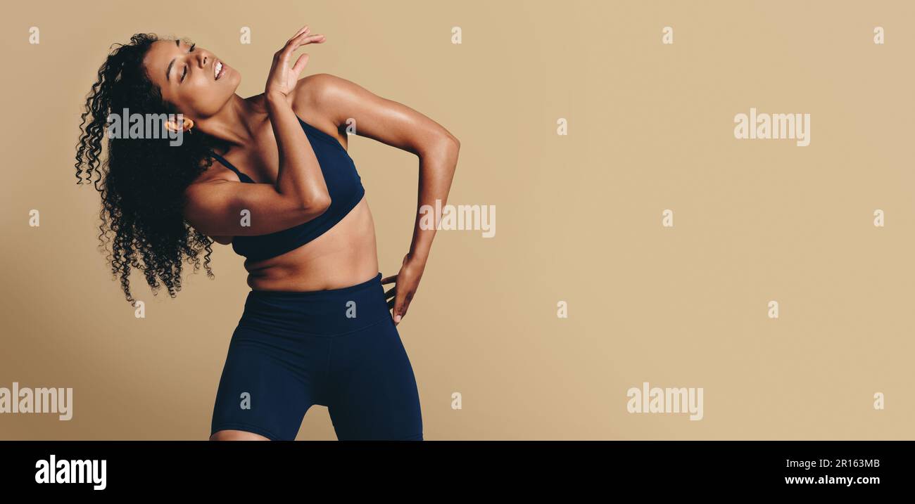 Fit Woman in Sportbekleidung tanzt anmutig im Studio und zeigt ihre sportliche Stärke und Form. Sie inspiriert andere dazu, ihre eigene Athletik anzunehmen Stockfoto
