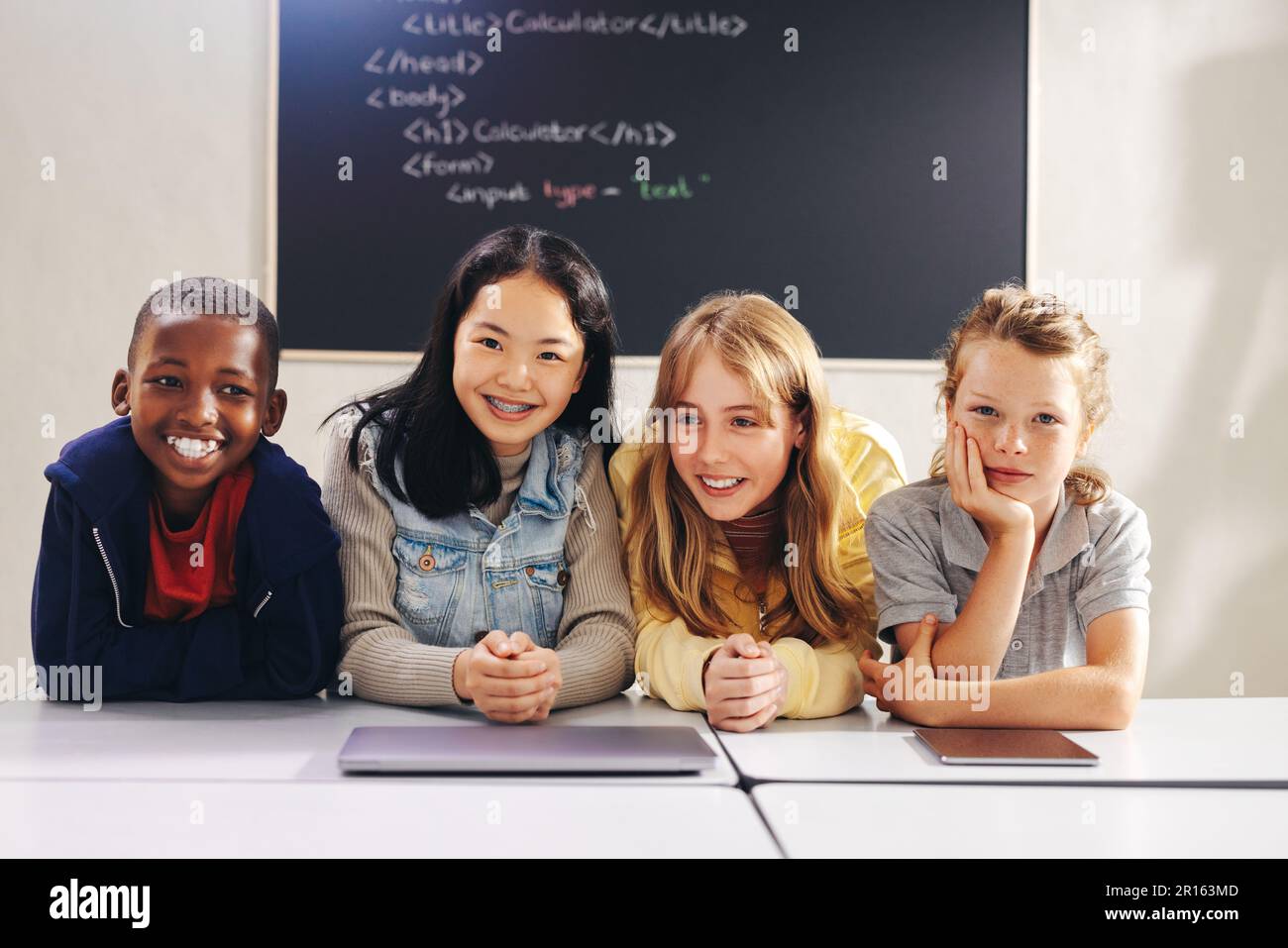 Verschiedene Grundschulkinder lächeln und schauen in einem Programmierkurs in die Kamera. Gruppe junger Schüler, die Programmieren und digitale Kompetenz in A erlernen Stockfoto