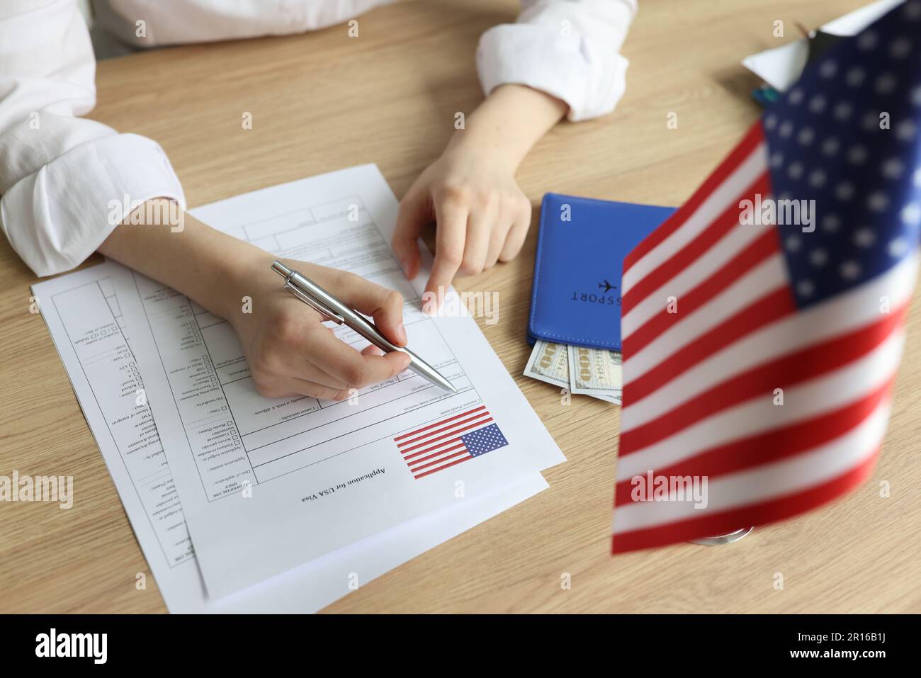 Junge Frau füllt das Visumantragsformular nahe der US-Flagge aus Stockfoto