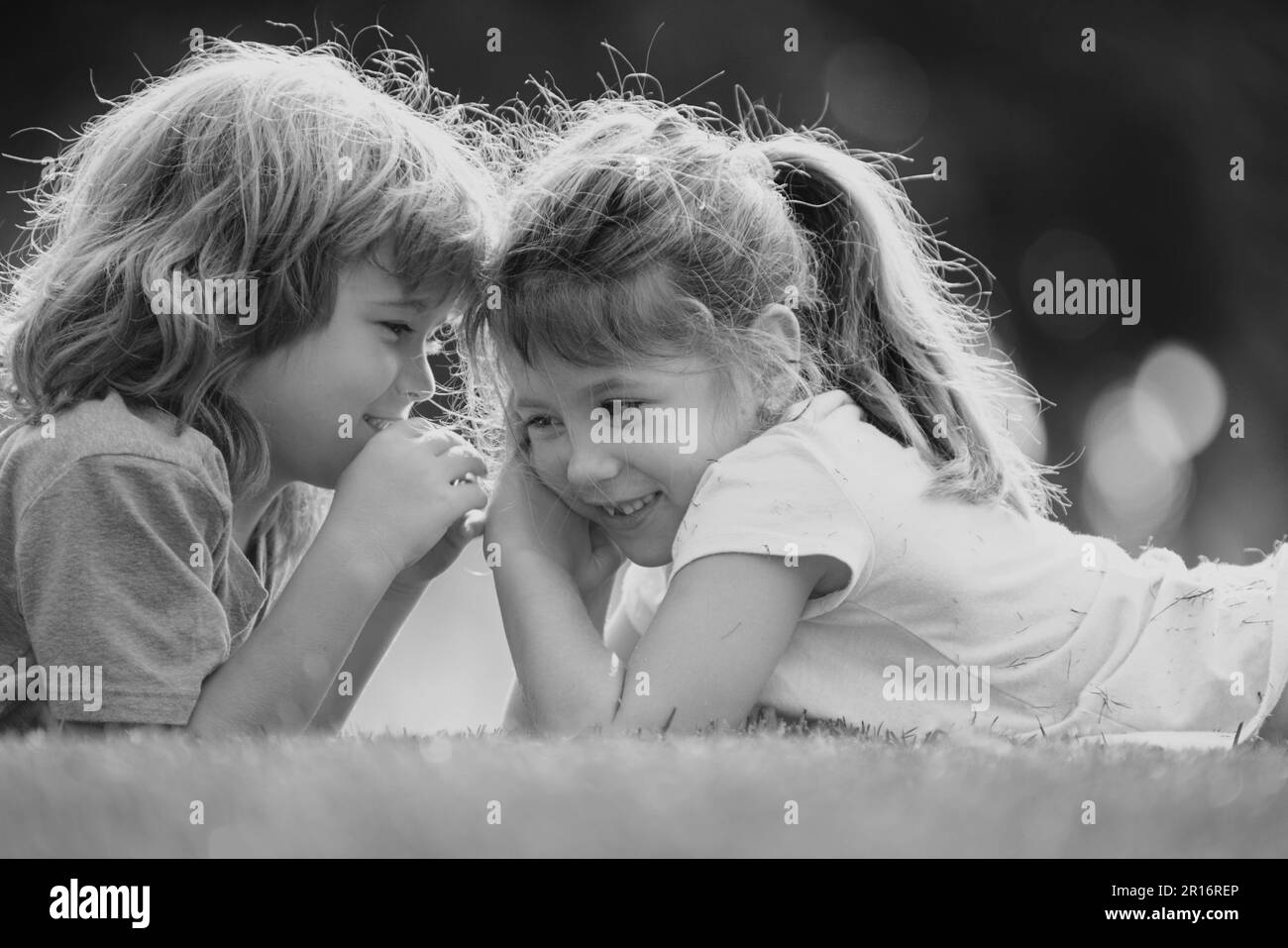 Kleiner Junge und Mädchen besten Freunde umarmt. Kinder küssen sich im Sommerpark mit Liebe. Kleine Freunde. Blonde Kinder Bruder und Schwester liegen auf Stockfoto