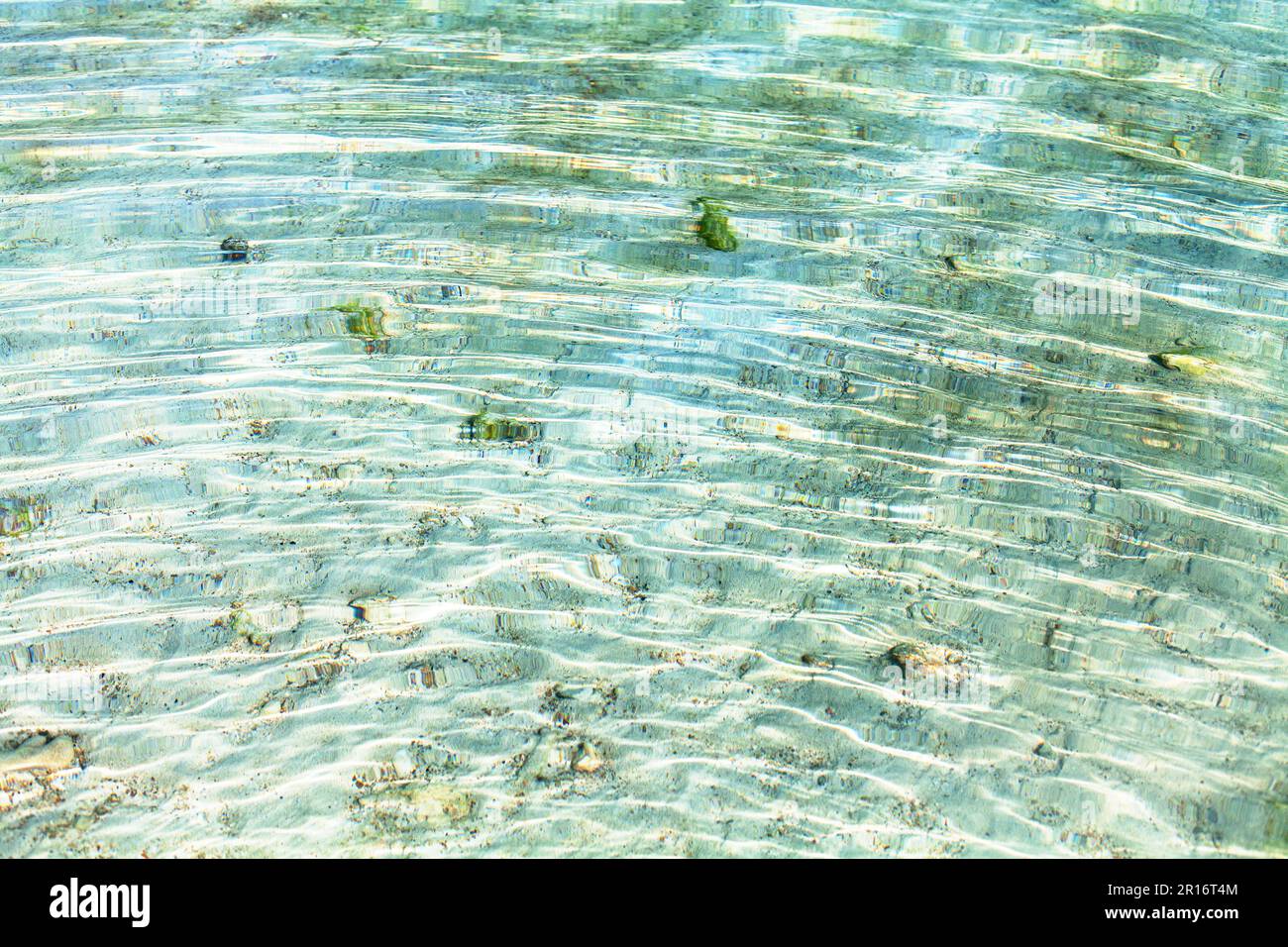 Meerwasserwellen Textur, Wellen auf der Wasseroberfläche, transparenter, hellblauer Blick auf das Meer, klarer aquatischer Hintergrund, Sonnenschein Reflexion, weißer Sand Stockfoto