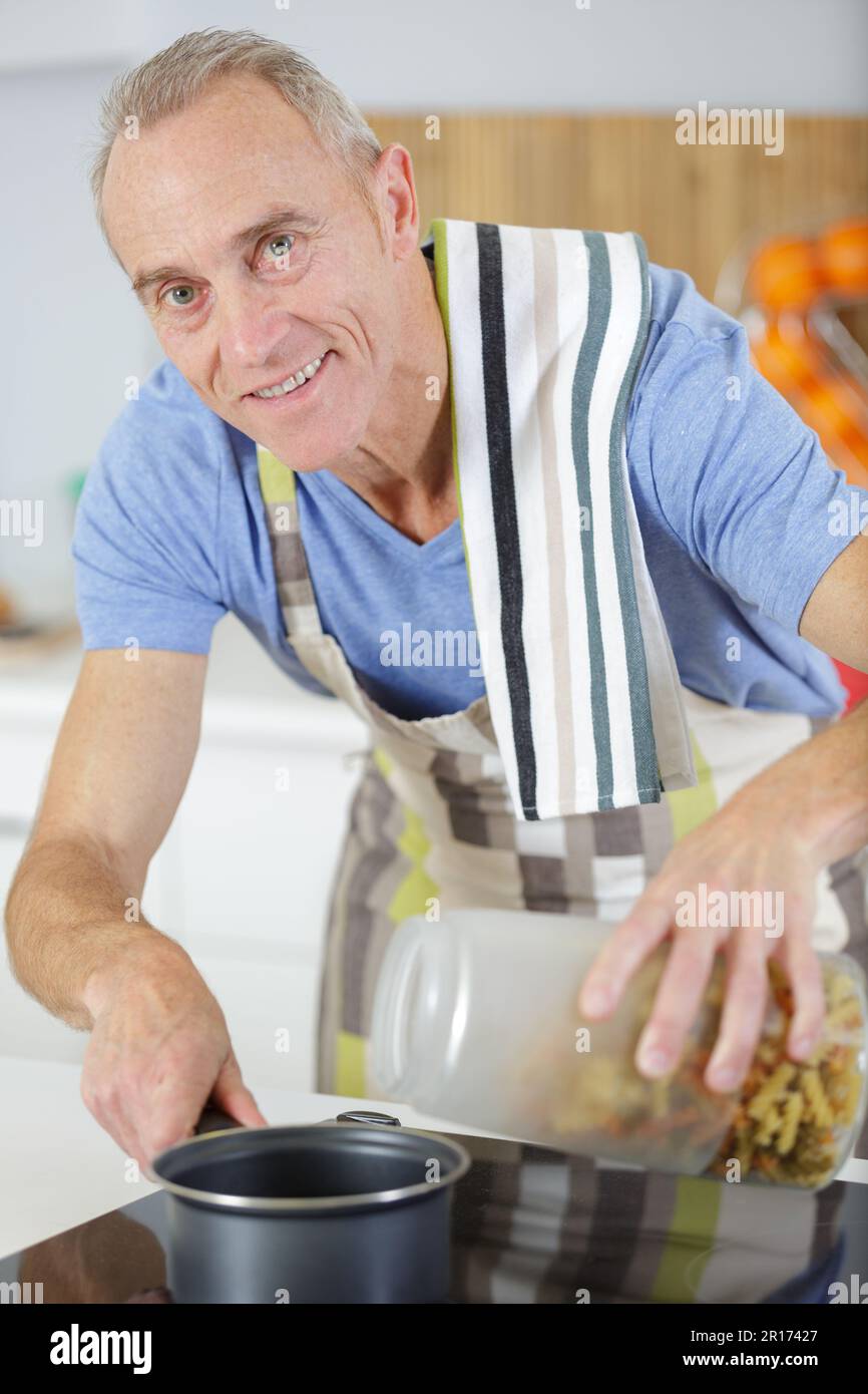 Ein älterer Mann mischt etwas in der Pfanne Stockfoto
