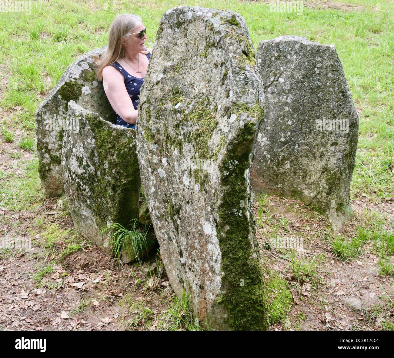 Eine Dame saß zwischen den Steinen in Les Megalithes, Passais la Conception, Domfront-en-Poiraie, Normandie, Frankreich, Europa am Donnerstag, den 11., den 2023. Mai Stockfoto