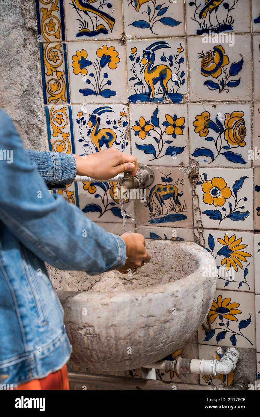Frau wäscht sich die Hände, alter Wasserspender in Porto Stockfoto