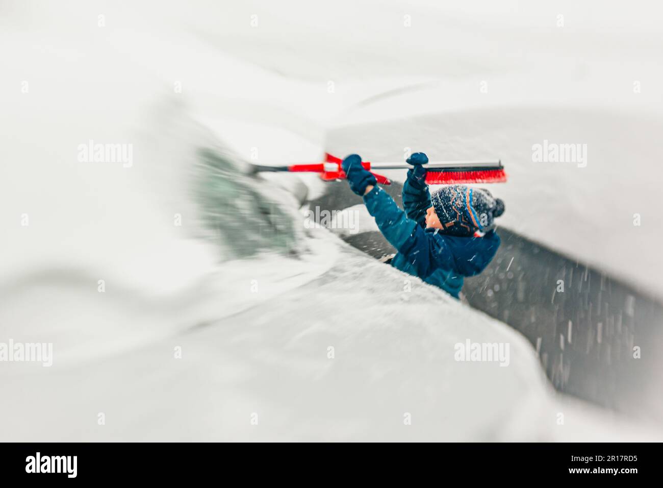 Hilfreicher Junge, der bei einem Schneesturm den Schnee räumt Stockfoto