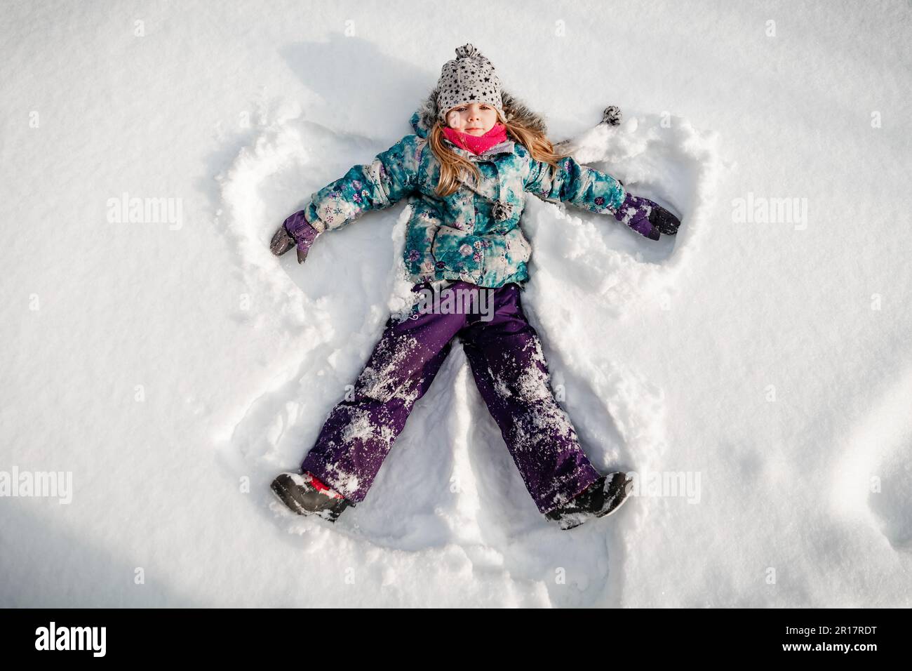 4 Jahre altes Mädchen, das einen Engel im Schnee macht Stockfoto