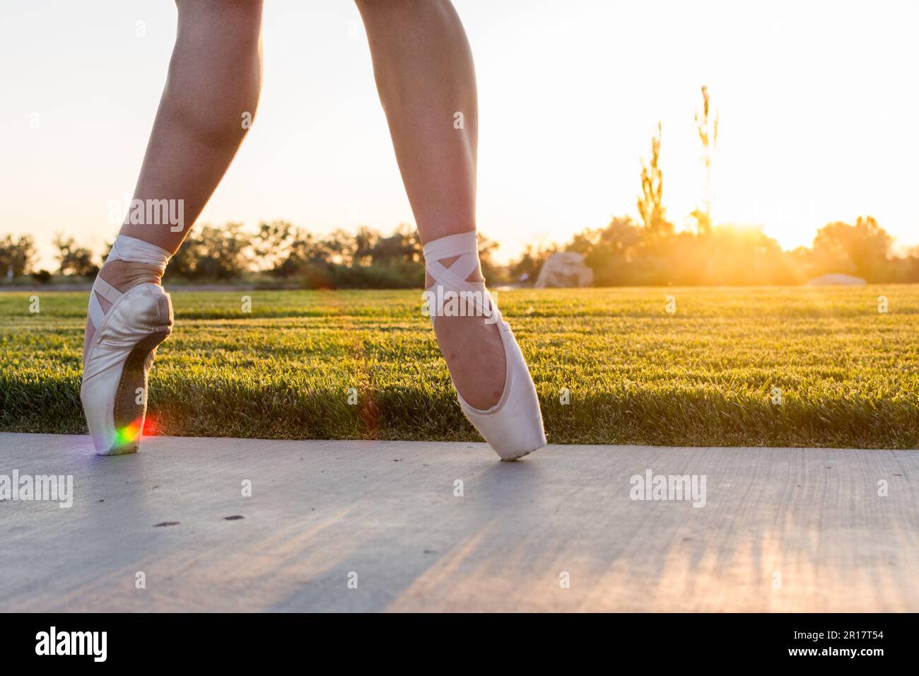 Füße einer Balletttänzerin in pointe-Schuhen bei Sonnenuntergang mit Regenbogen Stockfoto