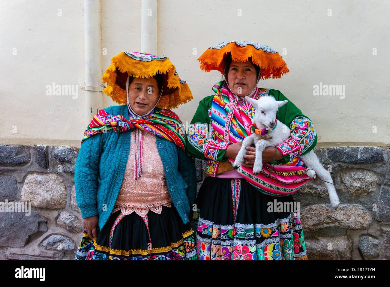 Zwei Frauen in traditioneller Kleidung und eine Ziege, die für Touristen posiert Stockfoto