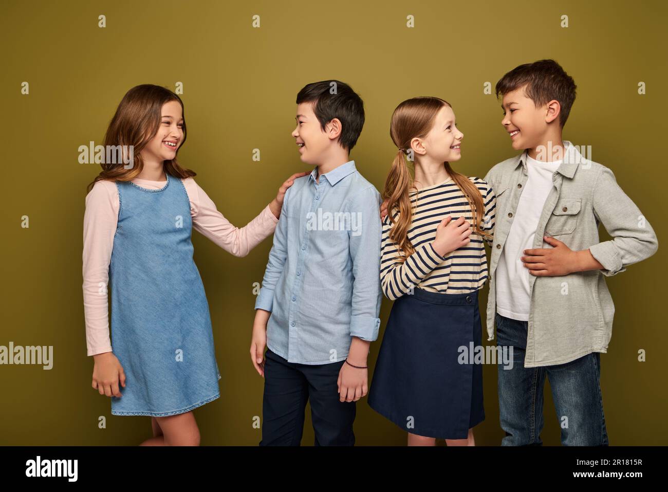 Lächelnde Kinder aus verschiedenen Rassen und Jugendliche in lässiger Kleidung, die miteinander sprechen, während sie den internationalen Tag des Kinderschutzes auf Khaki-Hintergrund feiern Stockfoto