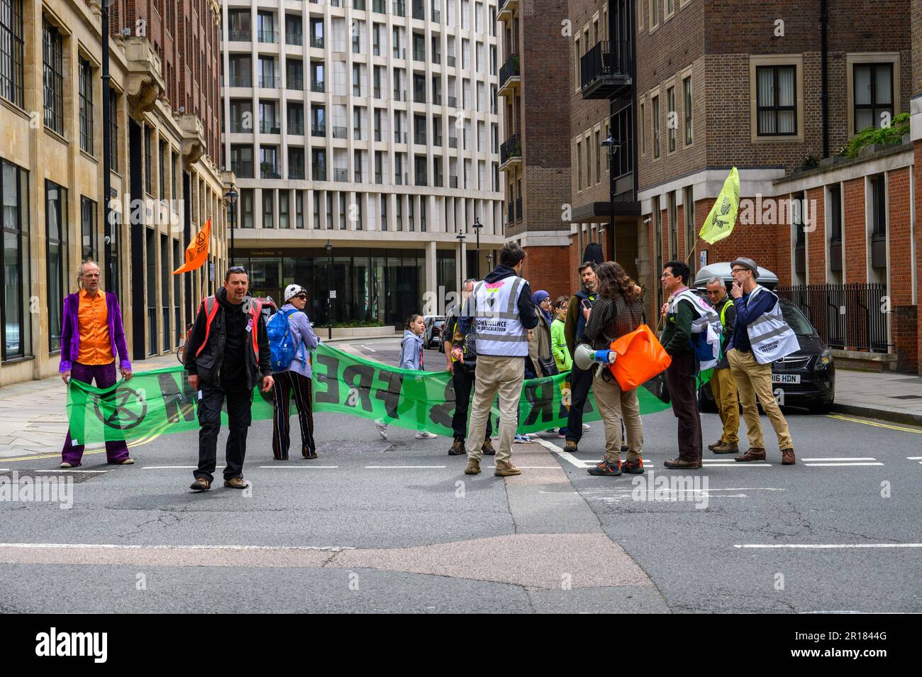 LONDON - 22. April 2023: Organisatoren und Demonstranten mit einem Banner stellen eine Straßensperre dar und zeigen ihr Engagement für die Ausrottung der Rebellion Cause duri Stockfoto